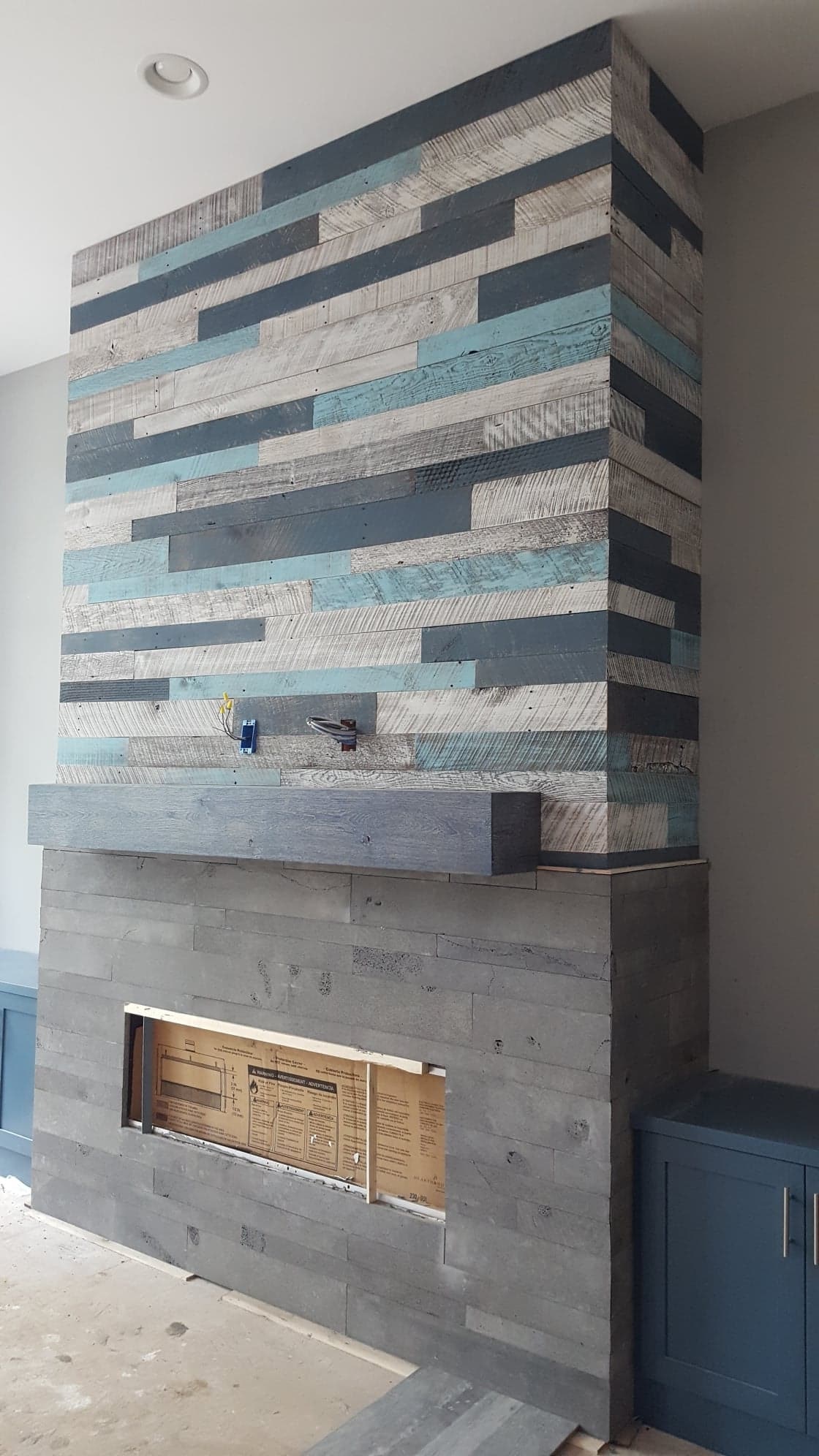 Fireplace featuring Norstone Planc Lavastone tiles on the bottom and multi colored Barnwood above the hearth to the ceiling