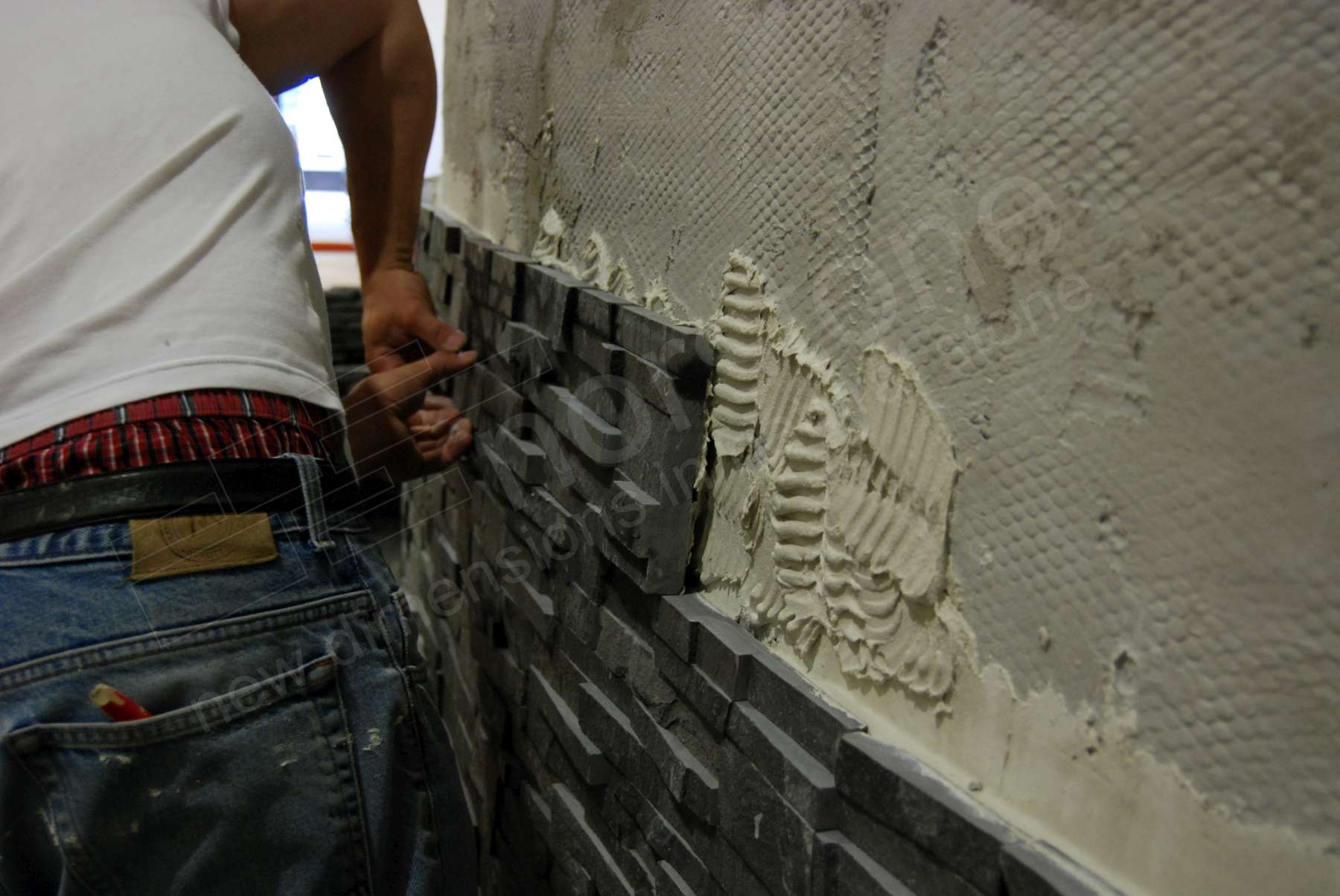 Closeup of man setting a Norstone stone veneer panel in place on cement board using modified thinset