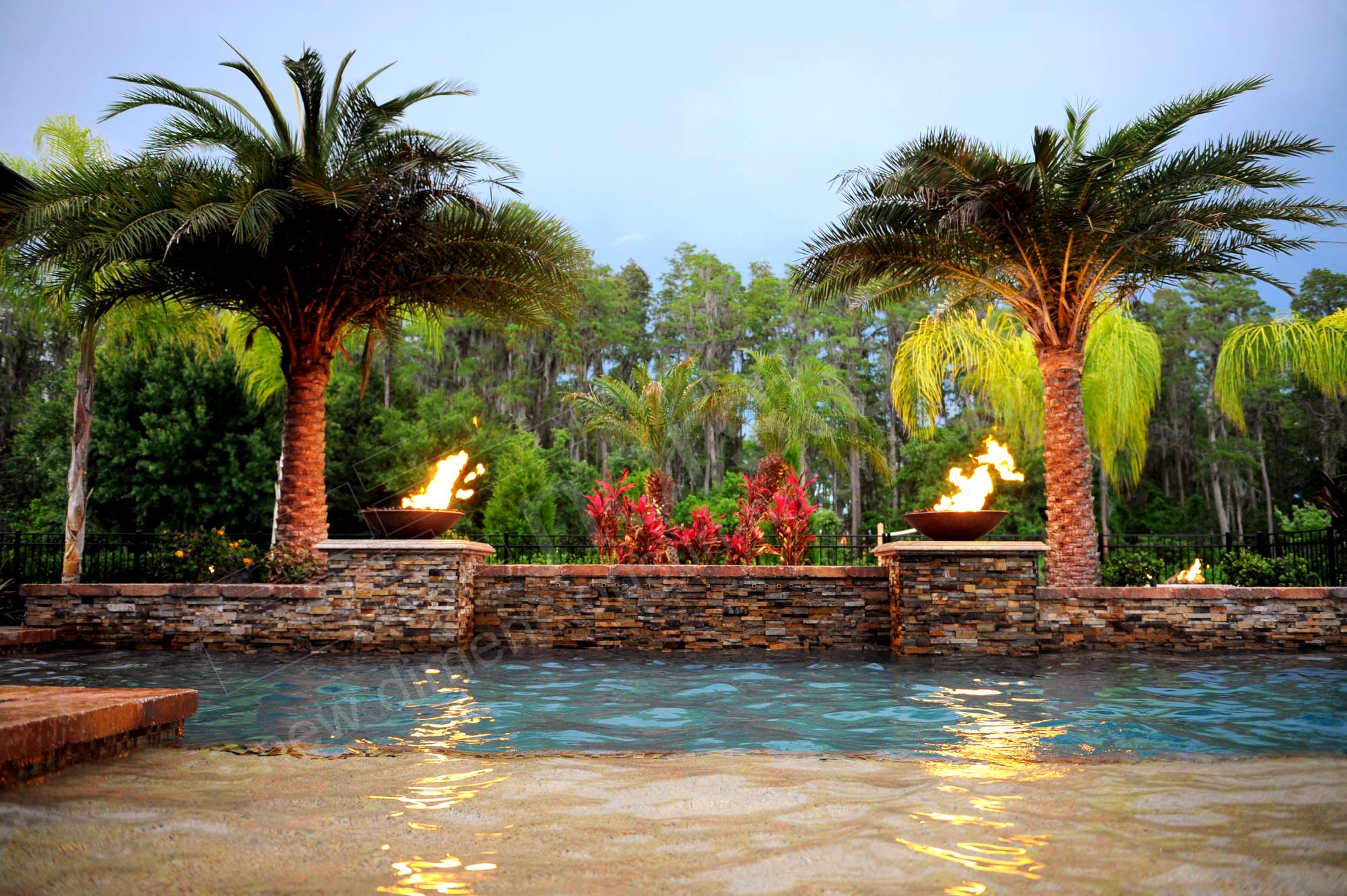 Fire bowls surrounding the spillway on a pool