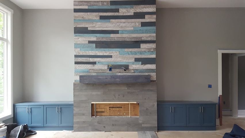 Norstone Platinum Planc Lavastone tiles in a mixed medium fireplace with barnwood strips above the mantle flanked by built in blue cabinets