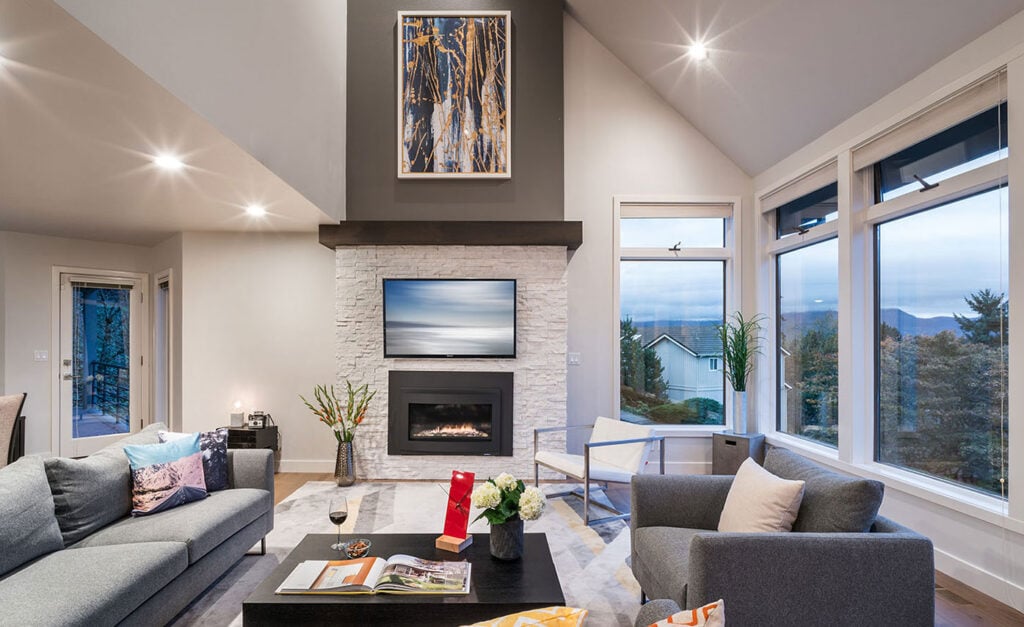 Norstone White Quartz Rock Panels on a large fireplace in an open living room with lots of natural light.
