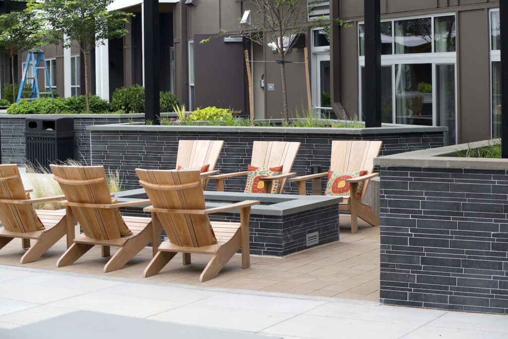 Grey Basalt LYNIA Tiles Cladding beautiful planter and landscape walls as well as linear fireplace surrounded by wood chairs.