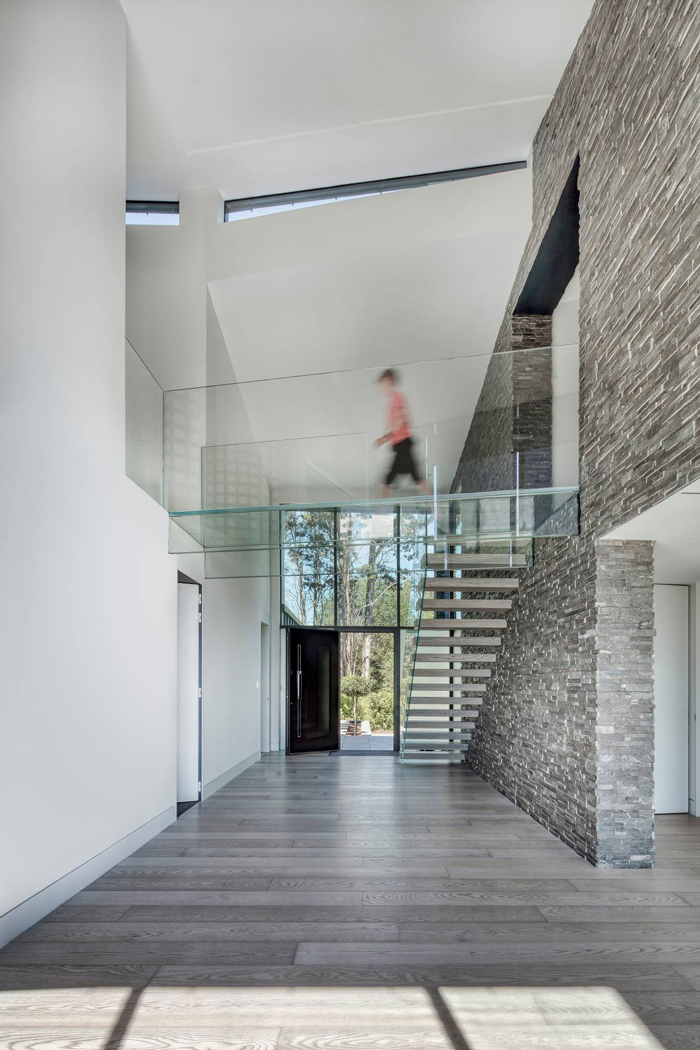 two story interior stone feature wall with walkway and glass railing