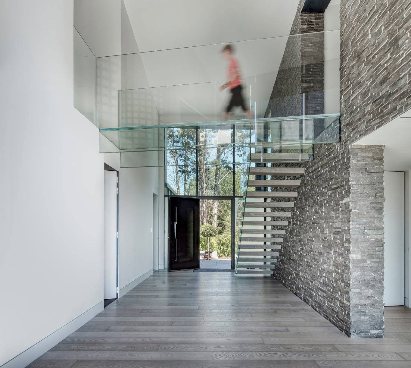 two story interior stone feature wall with walkway and glass railing